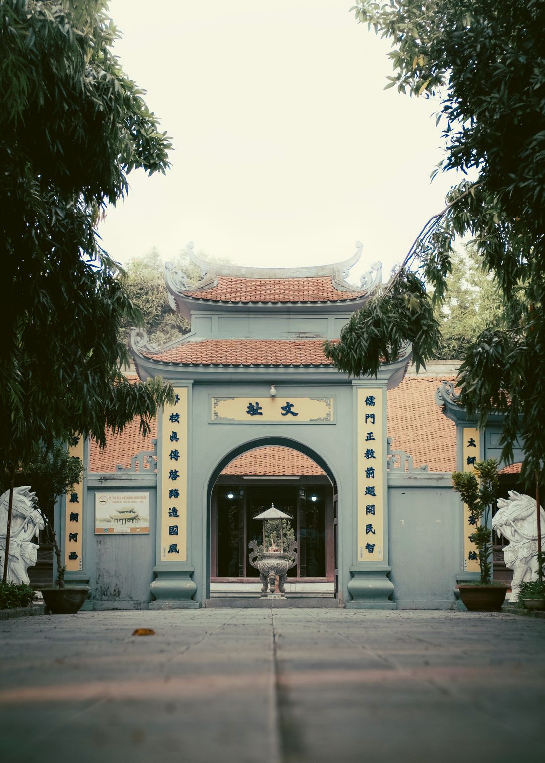 Cổng đền cổ với mái ngói mũi hài, câu đối và tượng nghê đá